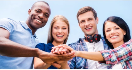 Group of diverse young people stacking hands to show teamwork and collaboration